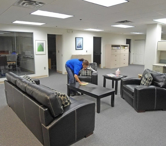 A dedicated cleaning operative carefully dusting a workspace with views of the Rock of Gibraltar, showcasing tailored cleaning services for local residents and businesses.