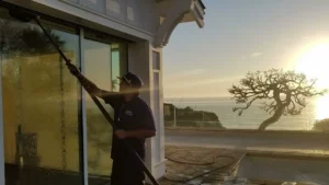 A friendly, uniformed professional providing trusted residential window cleaning services for a sunny home in Gibraltar, showcasing a crystal-clear view of the Mediterranean.