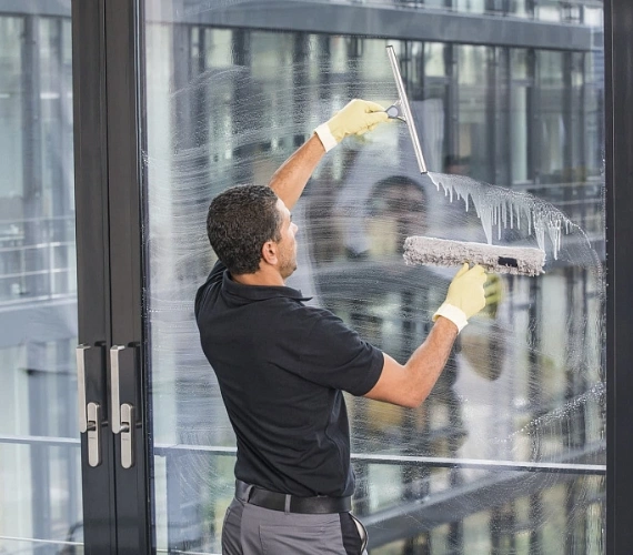 A fully insured window cleaning operative working discreetly outside a busy Gibraltar cafe early in the morning, ensuring zero disruption to daily business operations.