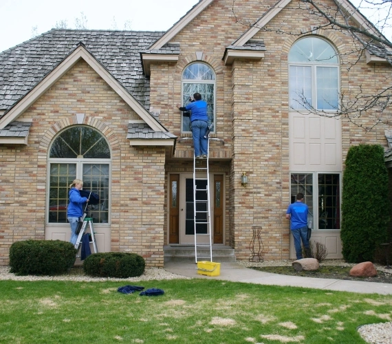 Rock Home Solutions technician cleaning a residential window in Gibraltar with pure water reach-and-wash system