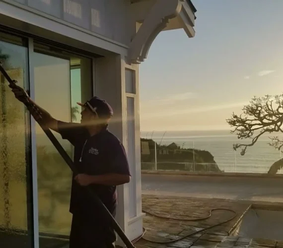 A friendly, uniformed professional providing trusted residential window cleaning services for a sunny home in Gibraltar, showcasing a crystal-clear view of the Mediterranean.