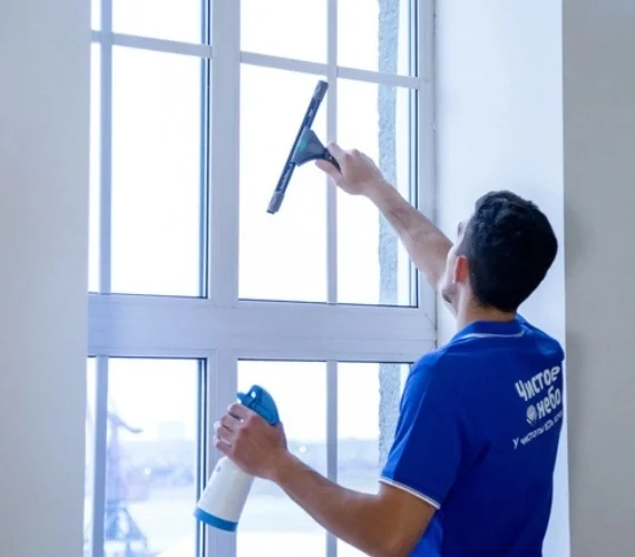 A professional window cleaner using a pure-water pole system on the exterior glass of a Gibraltar property, providing complete inside and out building maintenance.