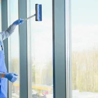 Expert providing commercial window cleaning services for a modern glass storefront and office building in Gibraltar.