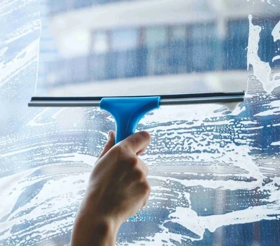 Professional window cleaners washing exterior glass, frames, and sills on a sunny day in Gibraltar, leaving a streak-free finish.