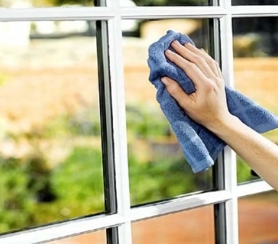Residential window cleaner safely washing the glass balcony and UPVC window frames of a luxury apartment in Gibraltar.